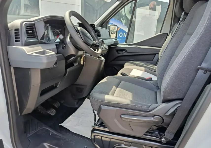 Vue intérieure côté conducteur du Renault Master 2025, sièges gris et tableau de bord avec écran tactile.