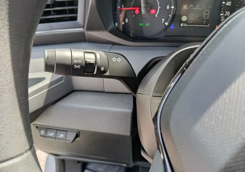 Gros plan sur la manette de clignotant noire et le tableau de bord du Renault Master 2025, intérieur gris foncé.