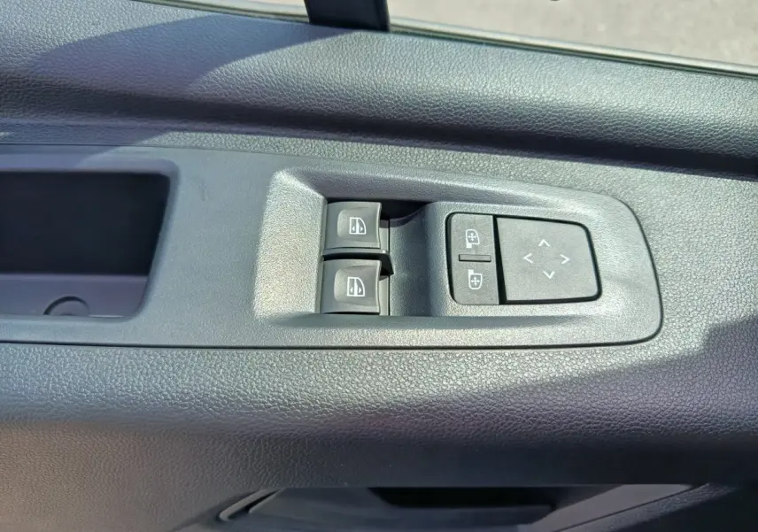 Commandes des vitres électriques et réglage des rétroviseurs sur la porte intérieure côté conducteur du Renault Master blanc.
