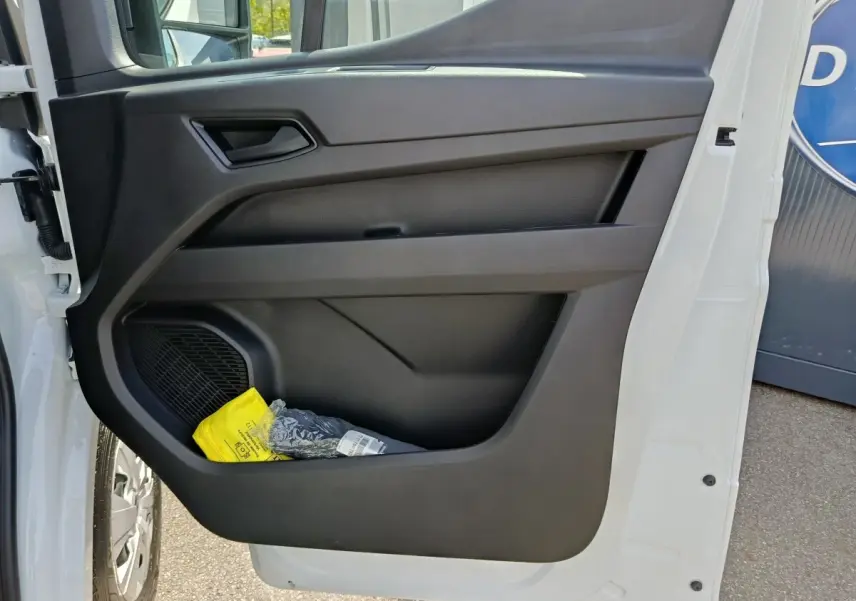 Vue rapprochée de la porte avant gauche blanche du Renault Master avec rangement et haut-parleur intégré.