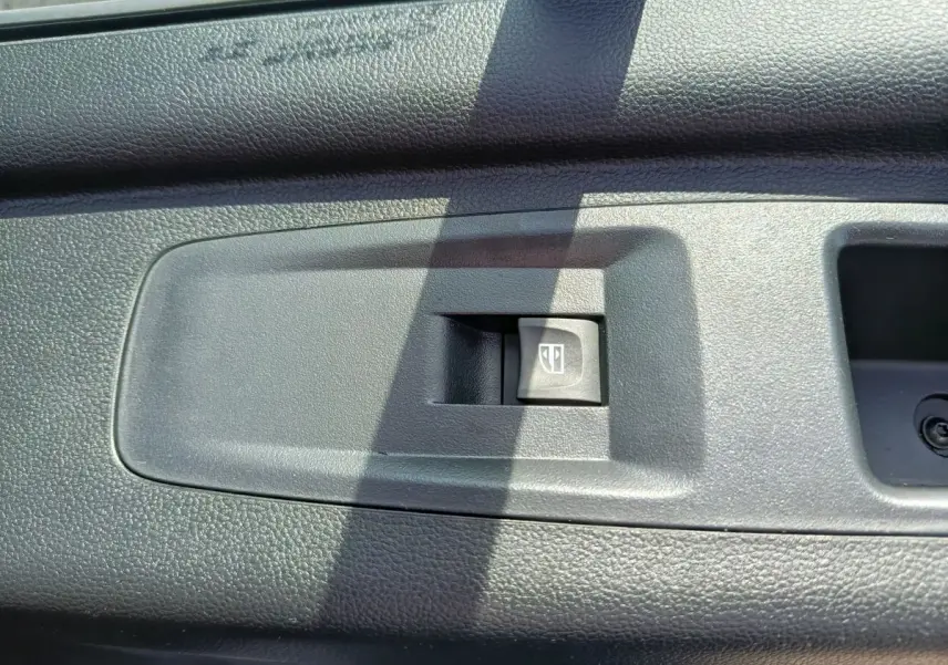 Gros plan sur l'interrupteur de commande de vitre électrique noir dans l'habitacle du Renault Master blanc.