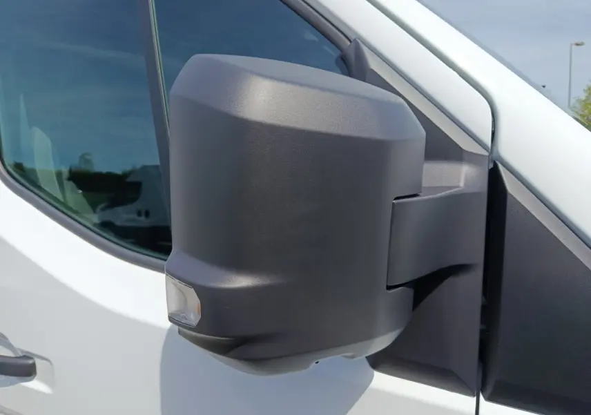 Gros plan sur le rétroviseur droit noir du Renault Master blanc, avec fenêtre latérale en arrière-plan.