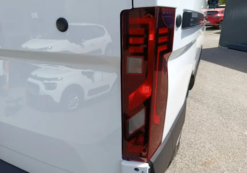 Gros plan sur le feu arrière droit du Renault Master blanc, mettant en valeur la surface rouge et les détails lumineux.