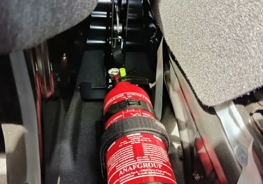 Gros plan intérieur sous siège montrant un extincteur rouge fixé dans un Renault Master blanc 2025.