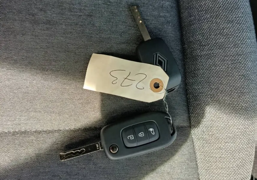 Gros plan sur deux clés Renault posées sur un siège tissu gris, avec une étiquette numérotée 0233.