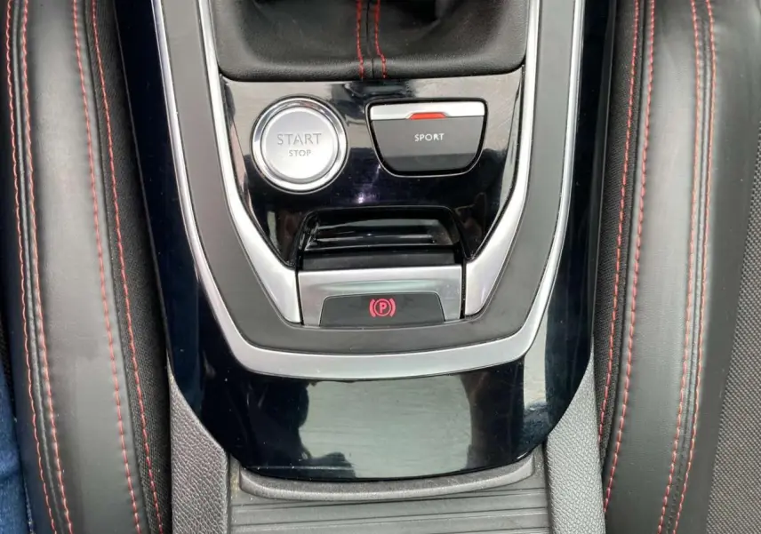 Vue rapprochée de la console centrale noire avec bouton Start/Stop et mode Sport sur Peugeot 308 rouge GTi 2016.