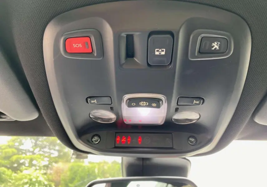 Vue du plafonnier intérieur avec bouton SOS rouge et commandes d'éclairage du Peugeot 308 GTi rouge 2016.