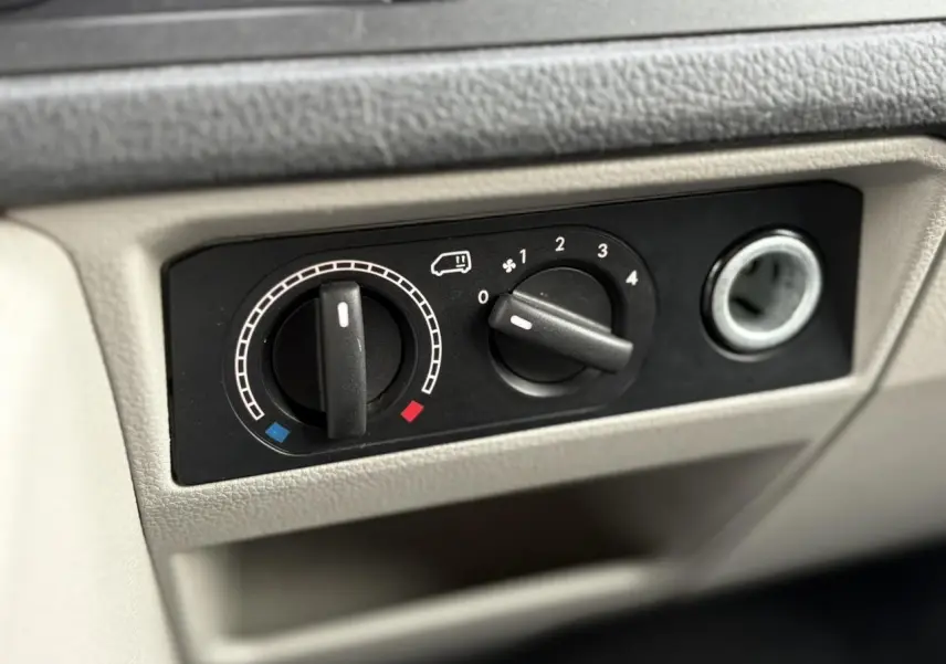 Gros plan sur les commandes de chauffage et ventilation du tableau de bord beige du Volkswagen Transporter 2017 jaune et blanc.