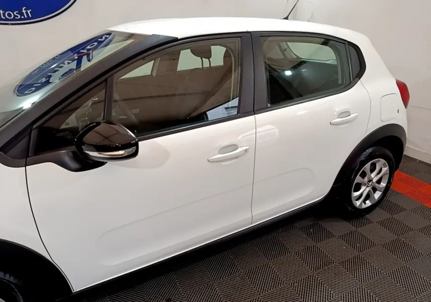 Profil côté gauche d'une Citroën C3 blanche 2018 avec rétroviseurs noirs et jantes alliage visibles en intérieur showroom.