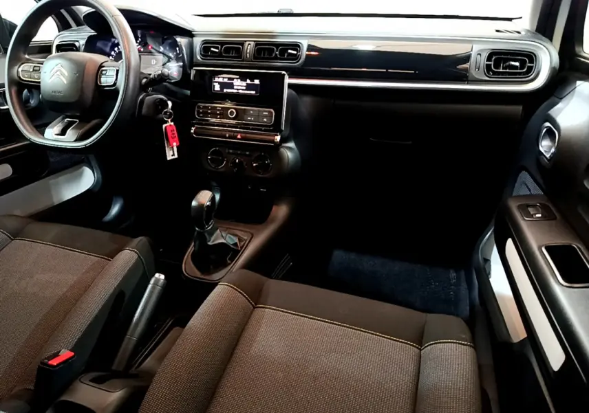 Intérieur avant droit de Citroën C3 blanc 2018, tableau de bord noir avec écran central et boîte manuelle visible.