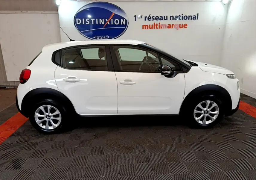 Profil côté gauche d'une Citroën C3 blanche PureTech 68 BVM Feel de 2018, en intérieur sur sol damier noir et rouge.