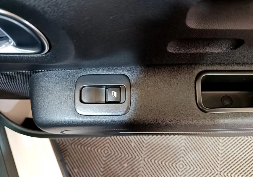 Gros plan sur le bouton de commande de la fenêtre côté conducteur d'une Citroën C3 blanche, intérieur noir.