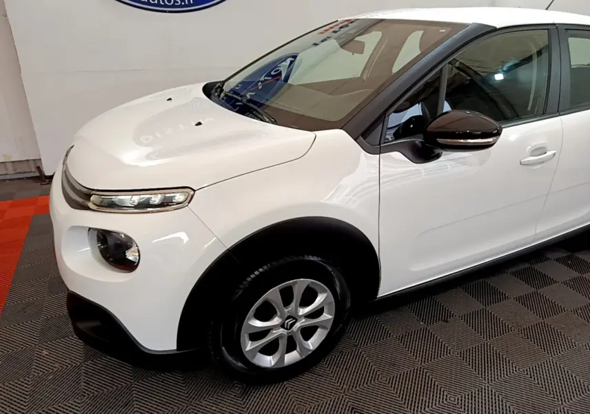 Vue 3/4 avant gauche d'une Citroën C3 blanche avec rétroviseurs noirs et jantes alliage argentées.