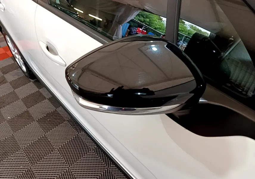 Rétroviseur noir brillant côté gauche d'une Citroën C3 blanche PureTech 68 BVM Feel vue en gros plan intérieur garage.