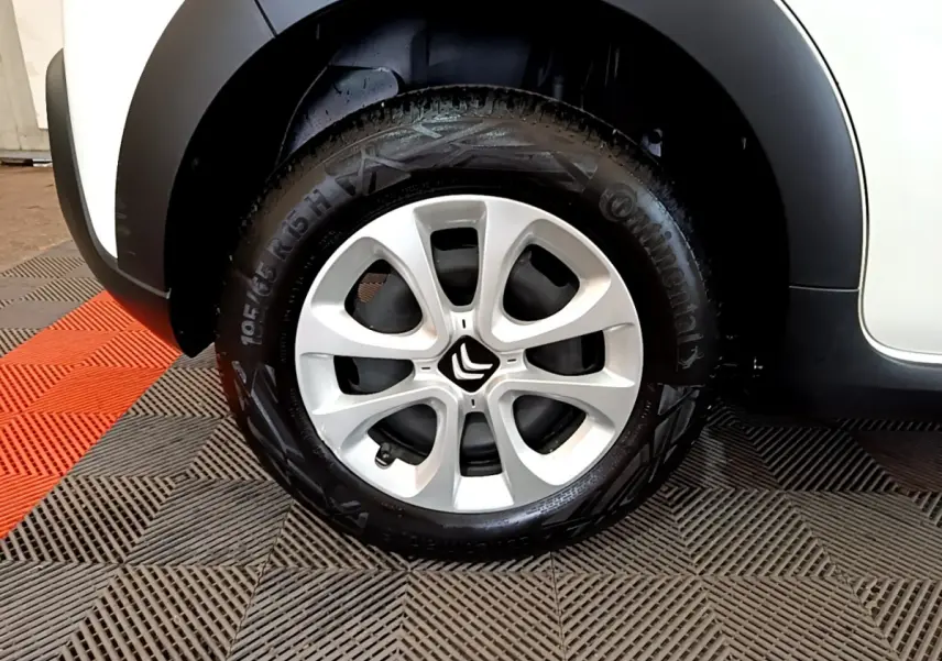 Gros plan sur la roue avant gauche de la Citroën C3 blanche, mettant en valeur la jante aluminium et le logo Citroën central.