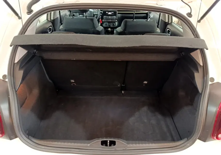 Coffre ouvert d'une Citroën C3 blanche vue de l'arrière, montrant l'espace de chargement et l'intérieur noir des sièges avant.
