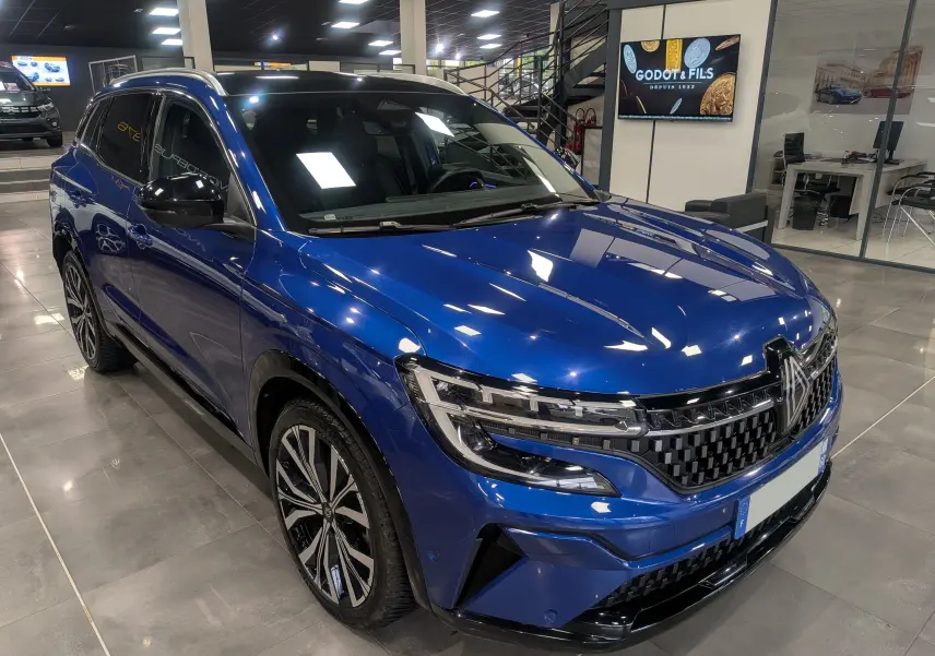 Renault Austral E-Tech Hybrid bleu Iron en 3/4 avant droit, mettant en valeur sa calandre et ses jantes bicolores.