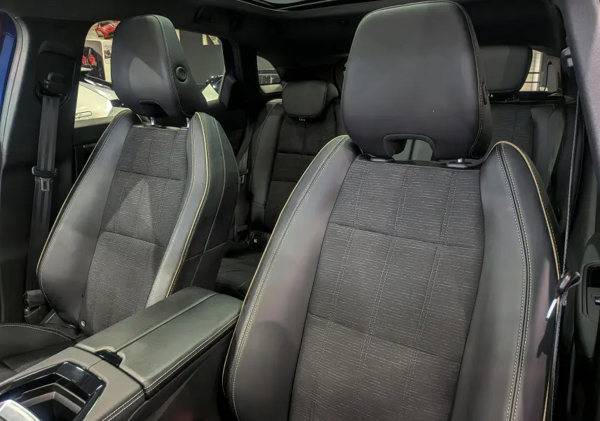 Intérieur du Renault Austral E-Tech Hybrid 2024, vue rapprochée des sièges avant en cuir noir avec surpiqûres jaunes.