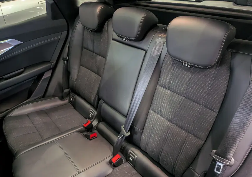 Vue intérieure des sièges arrière en tissu noir et cuir du Renault Austral E-Tech Hybrid 2024, avec ceinture de sécurité.