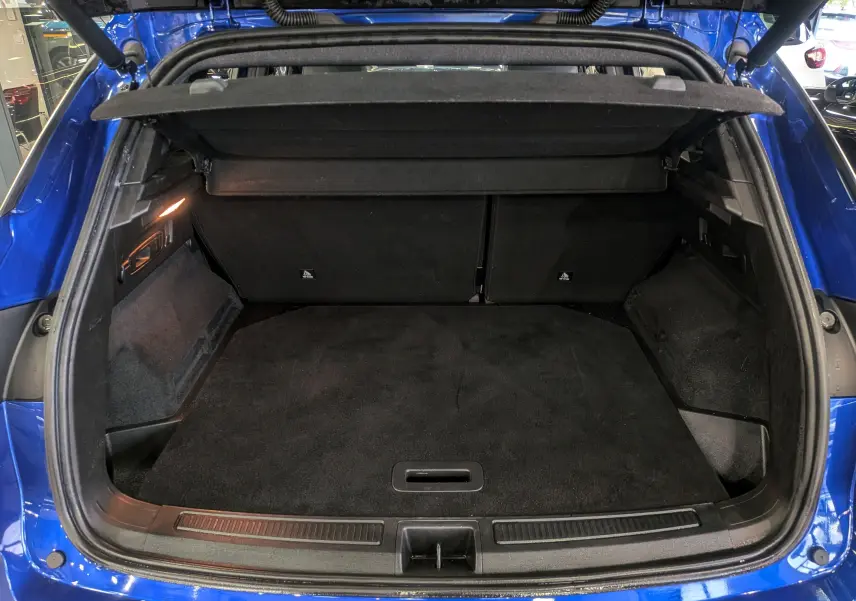 Coffre ouvert vu de l'arrière d'un Renault Austral E-Tech Hybrid bleu Iron, espace de chargement propre et spacieux.