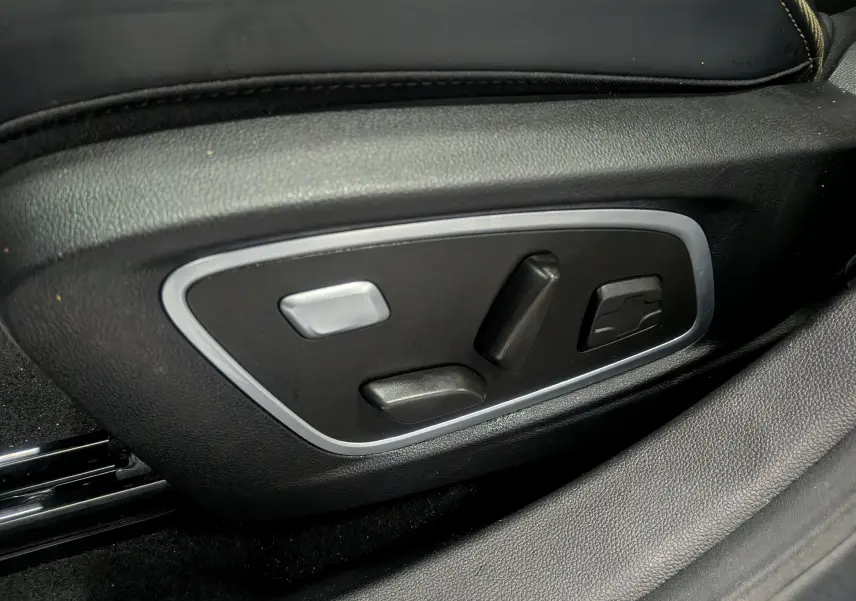 Gros plan sur les commandes électriques du siège conducteur en cuir noir du Renault Austral E-Tech Hybrid 2024.