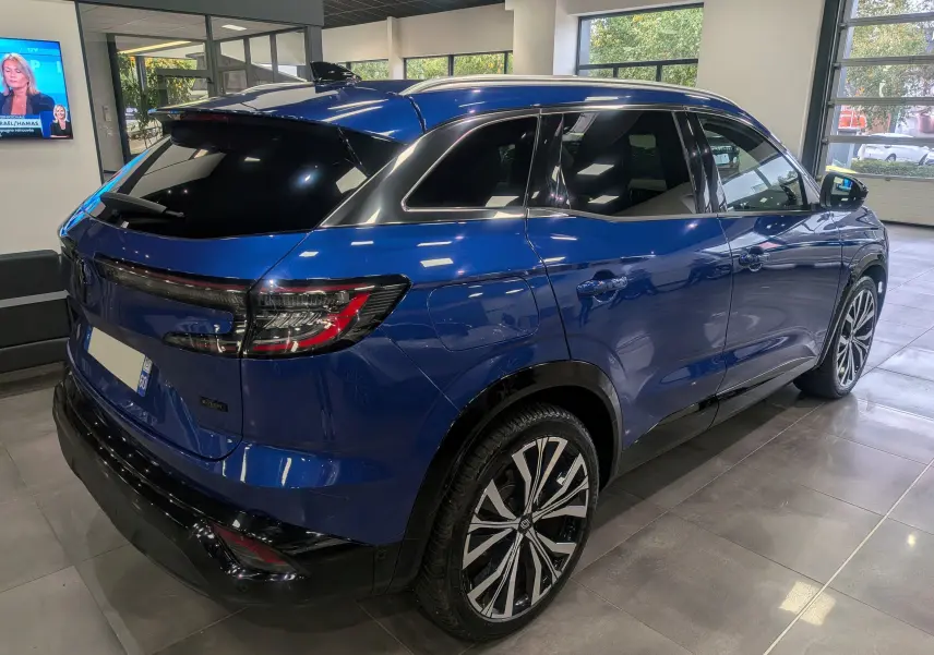 Vue 3/4 arrière droite du Renault Austral E-Tech Hybrid 200 ch Iconic en Bleu Iron, avec jantes bi-ton et vitres teintées.