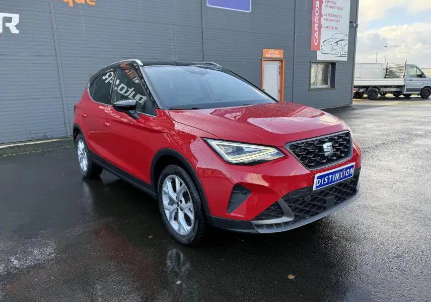 SEAT Arona rouge pur vue 3/4 avant droit, avec projecteurs LED et calandre noire distinctive.
