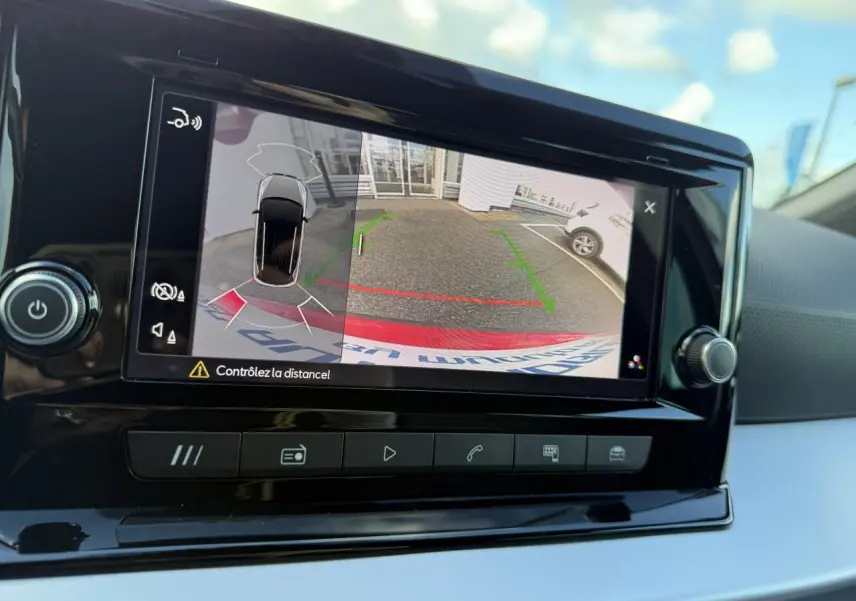 Écran central du SEAT Arona 2024 montrant la caméra de recul et l'assistance au stationnement en extérieur.