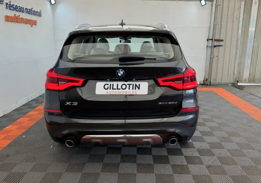 Vue arrière d’un BMW X3 xDrive30d gris foncé avec feux LED et double sortie d’échappement chromée.