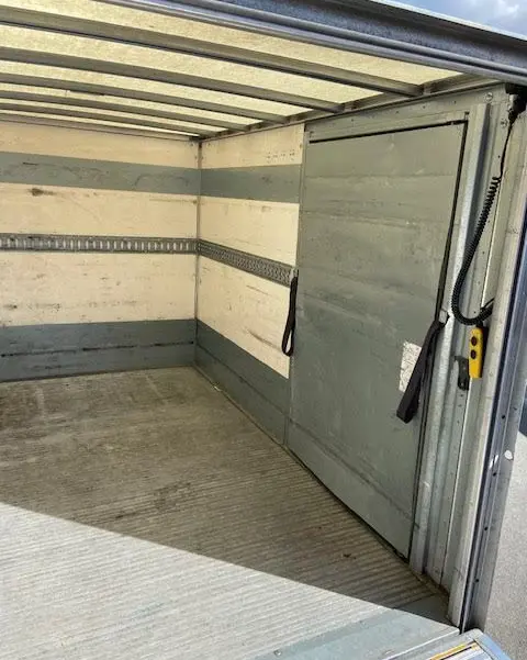 Intérieur de la caisse grise du Ford Transit Chassis Cabine jaune, vue depuis l'arrière avec hayon ouvert.