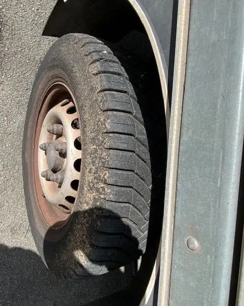 Gros plan sur la roue avant gauche usée du Ford Transit Chassis Cabine jaune, montrant la jante métallique rouillée.