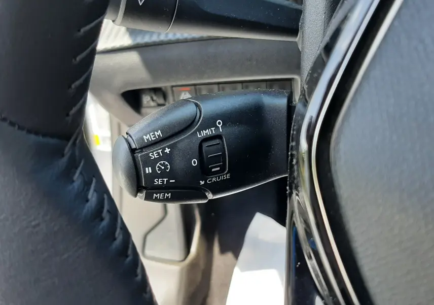 Gros plan sur la commande de régulateur de vitesse du Peugeot 2008 gris Artense, côté gauche du volant.