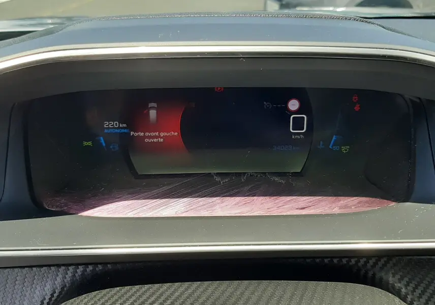 Tableau de bord numérique du Peugeot 2008 gris Artense, affichant porte avant gauche ouverte et compteur à 0 km/h.