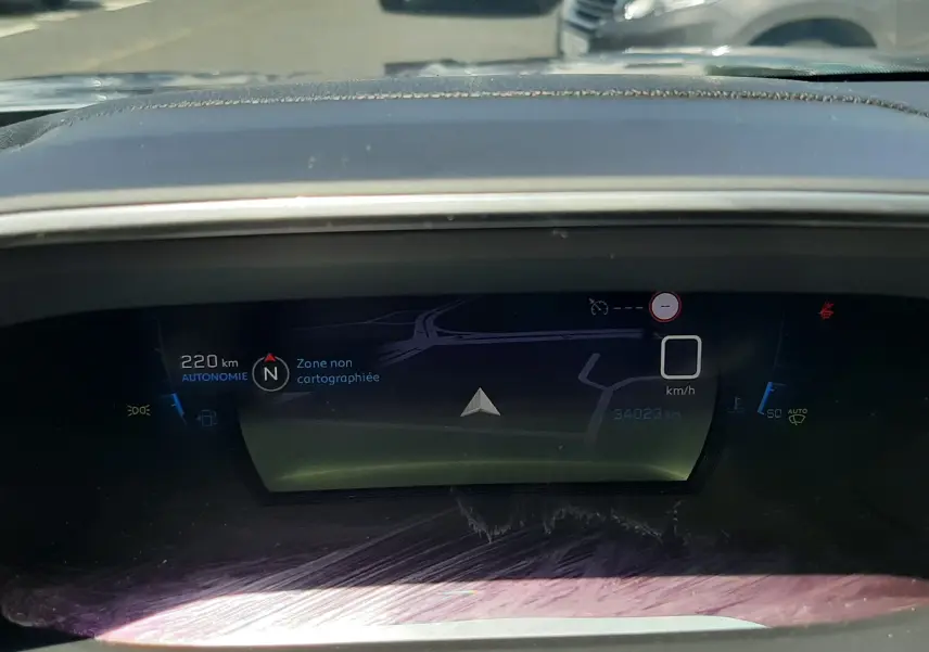 Tableau de bord numérique du Peugeot 2008 gris Artense, affichant la navigation et l'autonomie à 220 km.