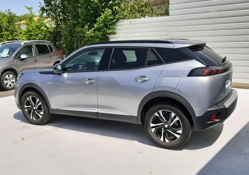 Peugeot 2008 gris Artense vu de profil côté gauche, avec toit noir et jantes alliage bicolores.