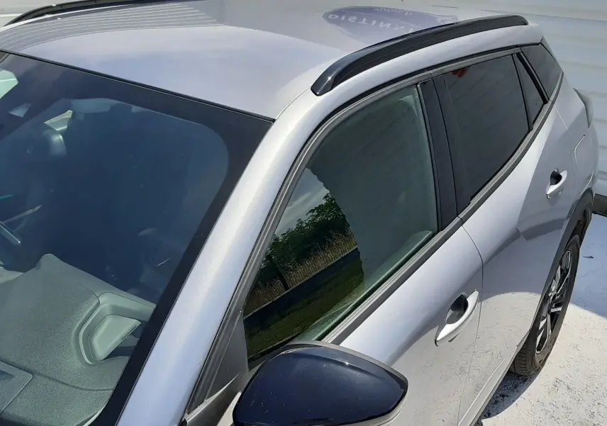 Vue 3/4 avant droit du Peugeot 2008 gris Artense, avec rétroviseur noir et barres de toit visibles.