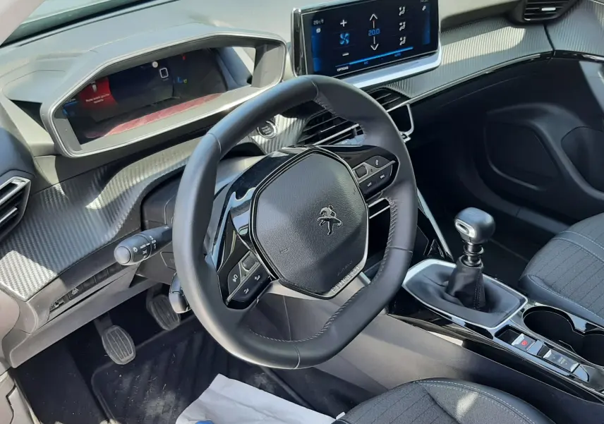 Intérieur du Peugeot 2008 2022, vue côté conducteur, volant compact, écran tactile et levier de vitesse manuel visibles.