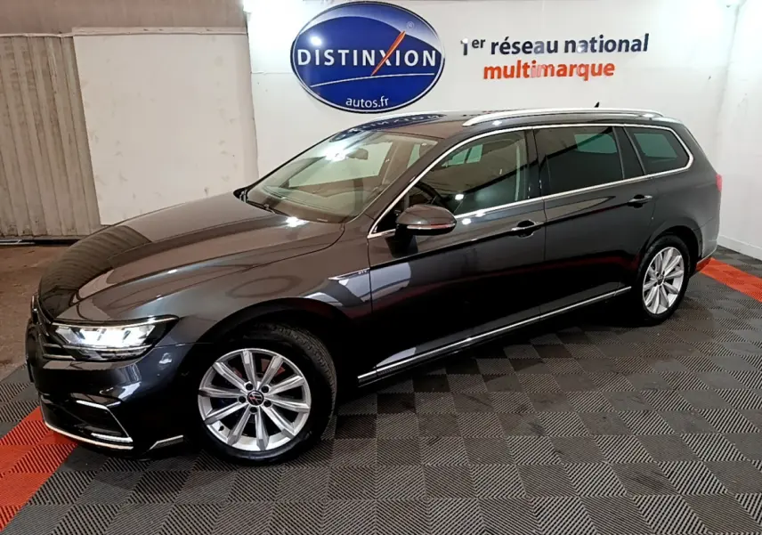 Volkswagen Passat SW hybride rechargeable gris foncé vue 3/4 avant droit, jantes alliage et feux LED allumés.