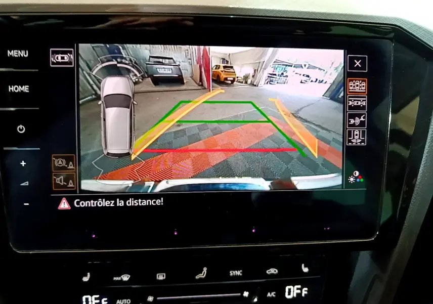 Écran tactile intérieur montrant la caméra de recul avec guidage dynamique d'une Volkswagen Passat gris foncé en stationnement.