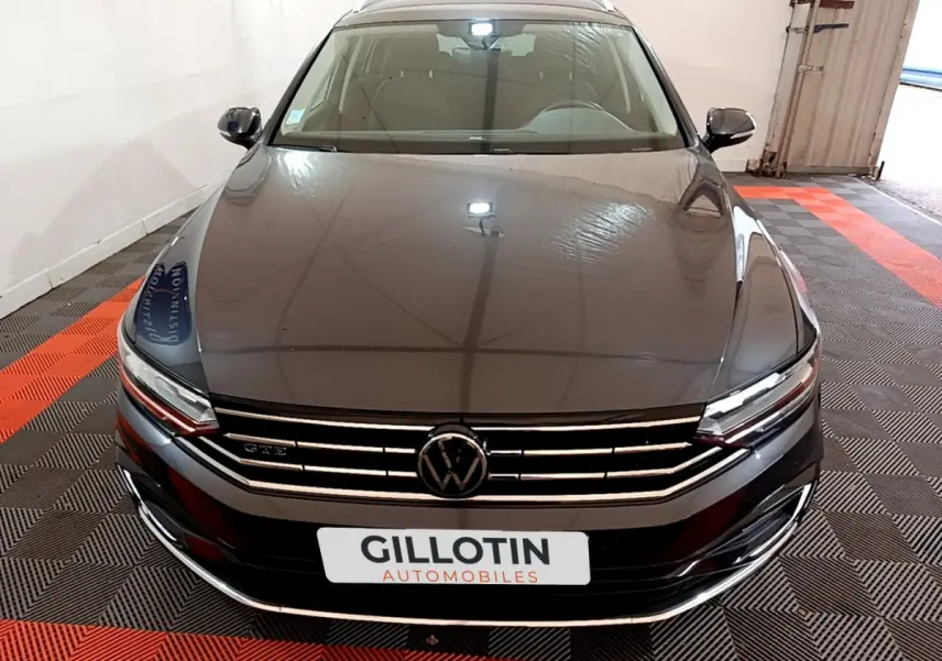 Vue avant d'une Volkswagen Passat GTE gris foncé stationnée sur sol à damier noir et rouge, avec calandre chromée.