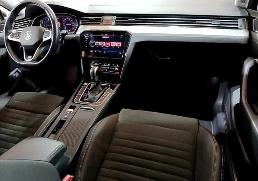 Intérieur avant de la Volkswagen Passat hybride rechargeable 2022, tableau de bord moderne avec écran tactile et volant cuir noir.
