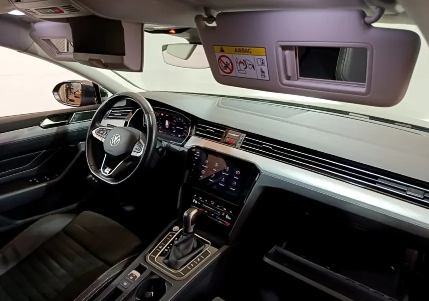 Intérieur avant de la Volkswagen Passat hybride rechargeable 2022, tableau de bord moderne avec écran tactile et volant cuir noir.