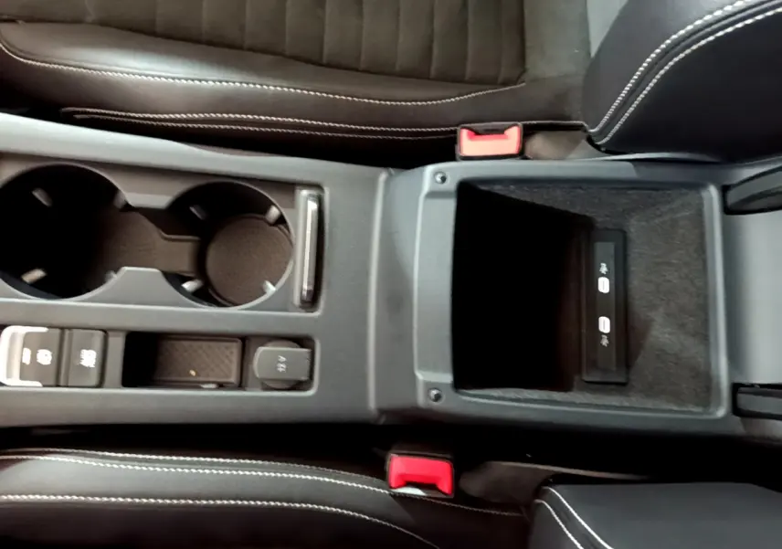 Vue plongeante sur la console centrale noire de la Volkswagen Passat GTE 2022, avec porte-gobelets et rangement USB.