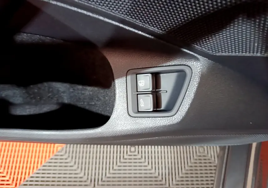 Gros plan sur les boutons d'ouverture du coffre et du réservoir dans la porte côté conducteur de la Volkswagen Passat gris foncé.