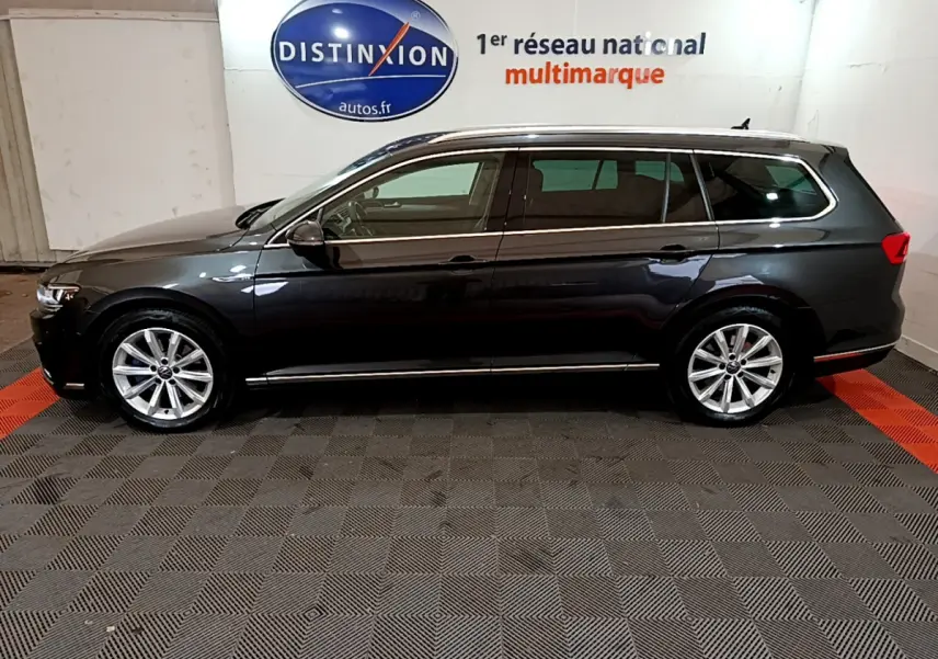 Profil côté gauche d'une Volkswagen Passat SW GTE hybride rechargeable gris foncé dans un showroom multimarque.