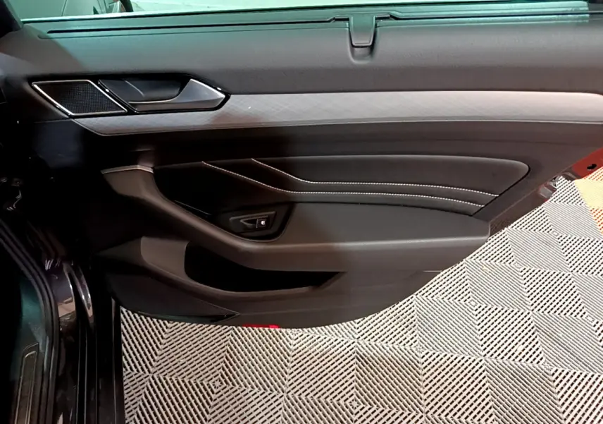 Porte intérieure côté gauche de la Volkswagen Passat GTE 2022 gris foncé, avec surpiqûres blanches et insert décoratif.