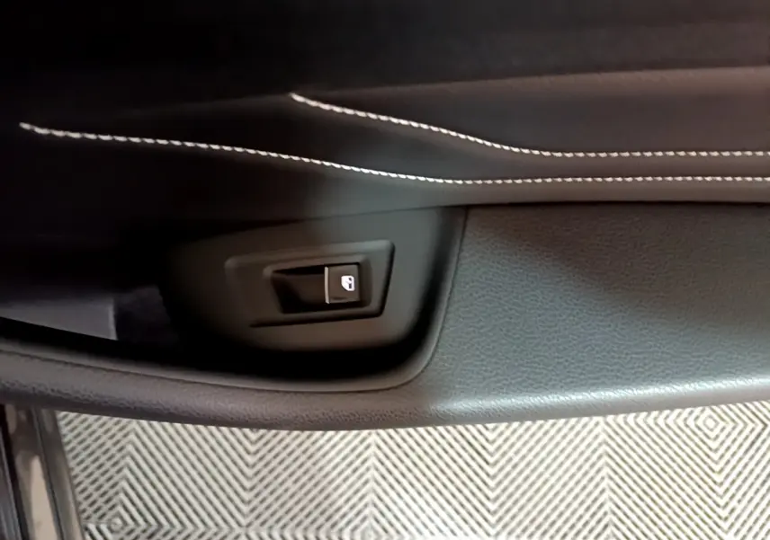 Bouton de déverrouillage de coffre sur la garniture intérieure noire avec surpiqûres blanches d'une Volkswagen Passat GTE hybride rechargeable.
