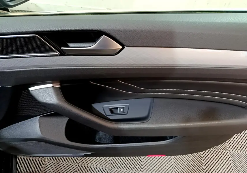 Gros plan sur la porte intérieure côté gauche de la Volkswagen Passat GTE 2022 avec surpiqûres blanches et poignée argentée.