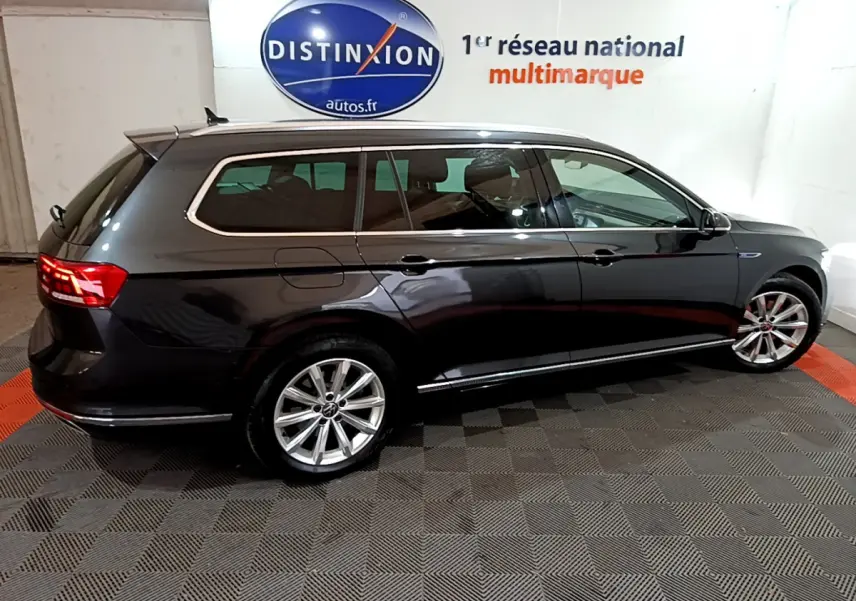 Volkswagen Passat SW hybride rechargeable gris foncé vue de profil côté gauche dans un showroom intérieur.