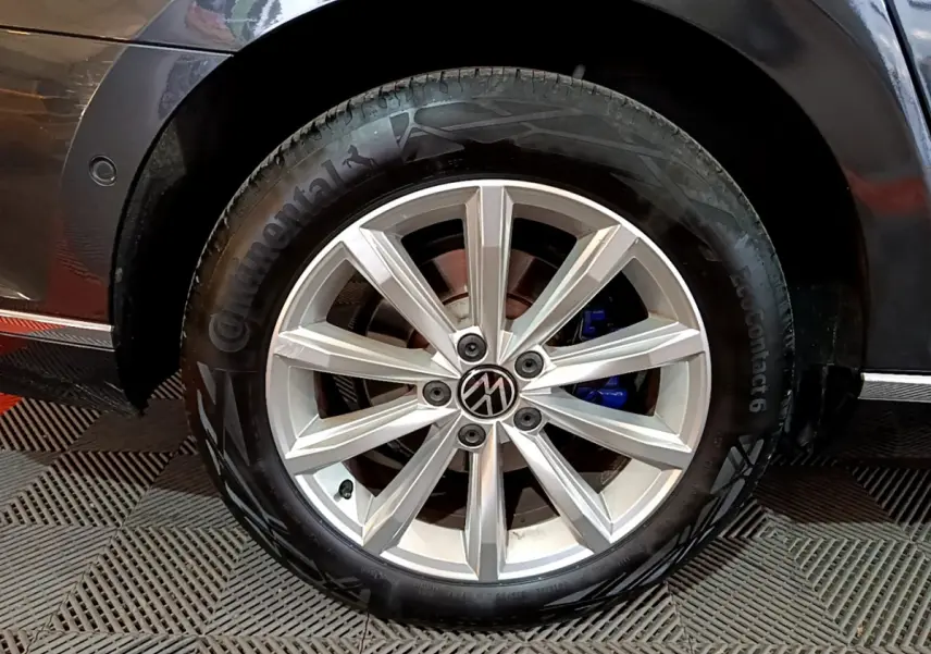 Gros plan sur la roue avant droite gris foncé d'une Volkswagen Passat hybride rechargeable avec jante alliage et étrier de frein bleu.